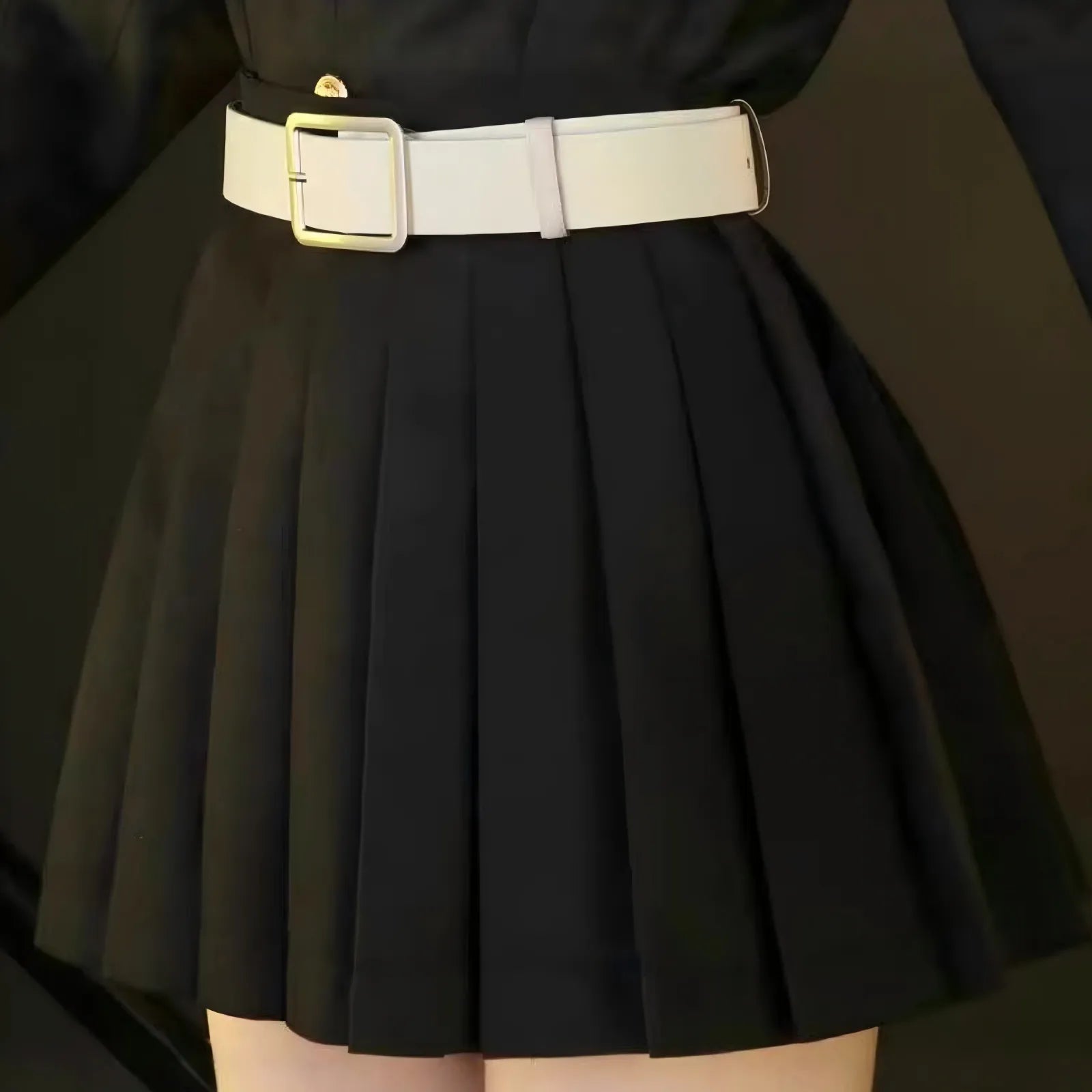 close‑up of white belt and black pleated skirt